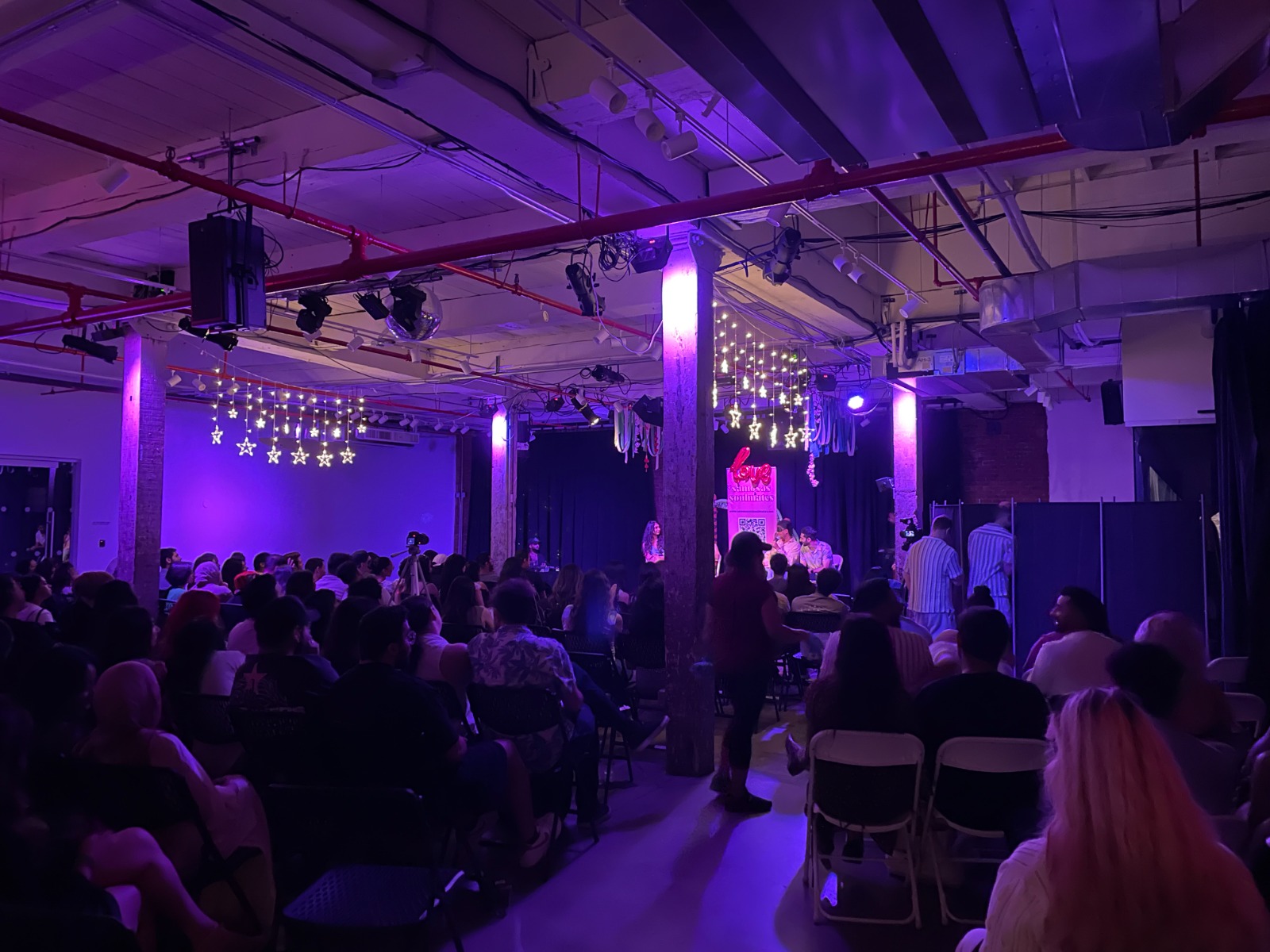 A full audience gathered for a panel in a purple-lit event space